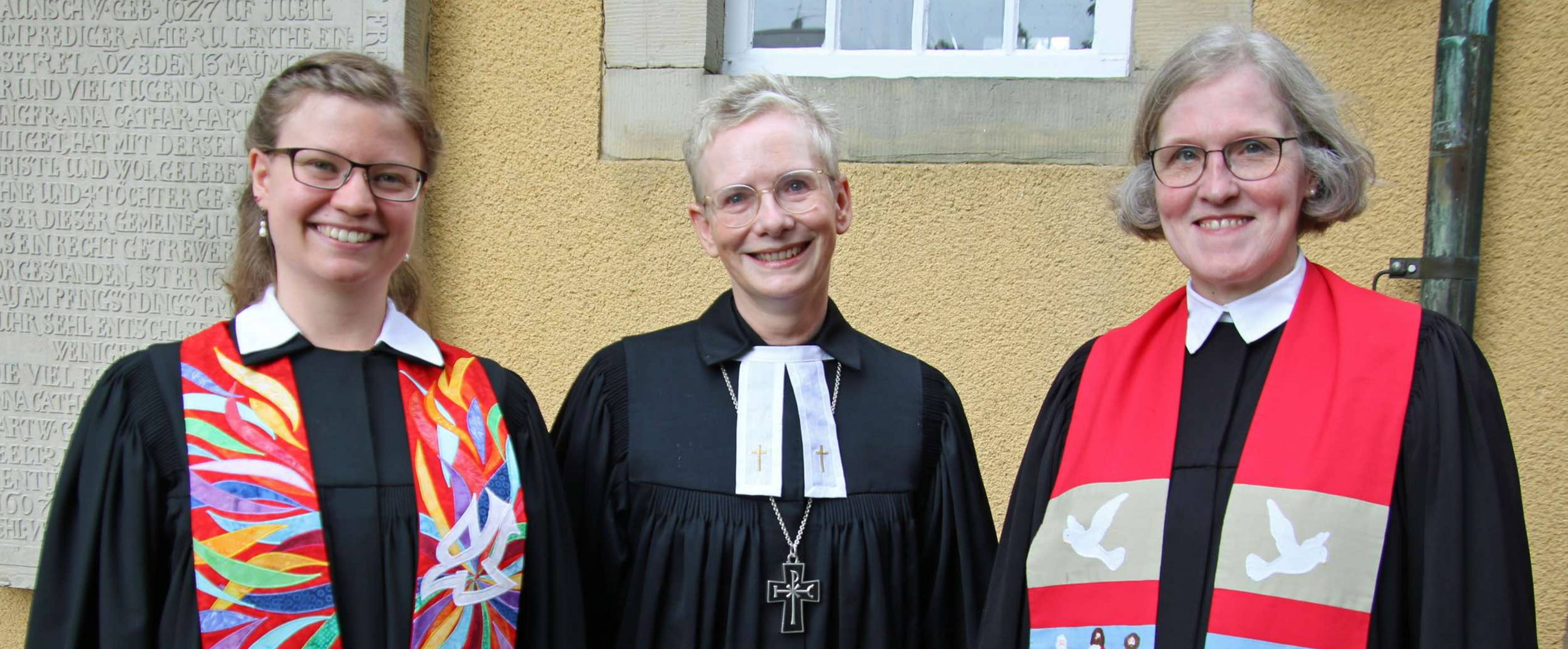 Auf dem Bild sind Laura Wolkenhauer, Regionalbischöfin Petra Bahr und Superintendentin Antje Marklein in Amtskleidung am Tag der Ordination zu sehen.