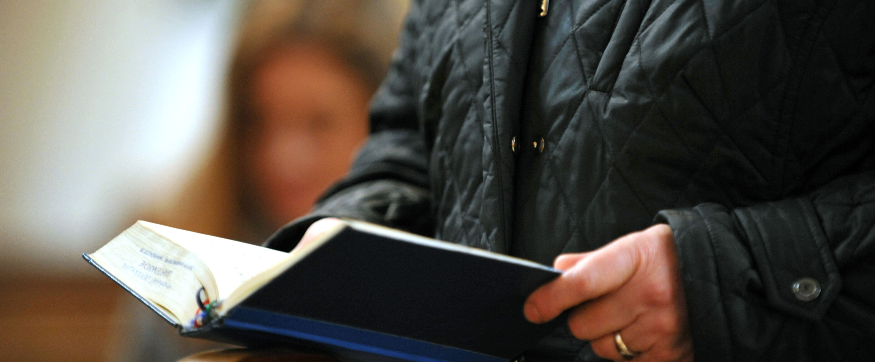 Eine Person hält ein Gesangbuch in der Hand.