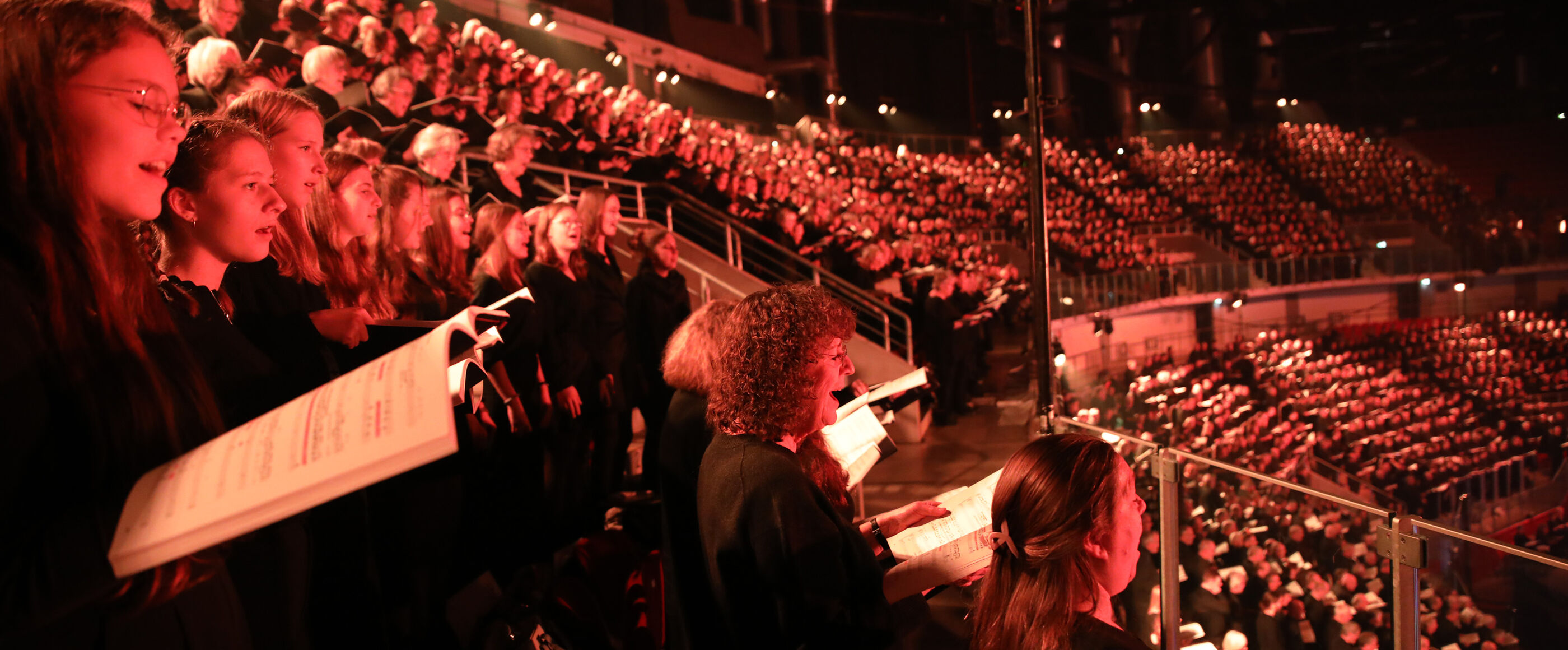 Viele junge Chorsängerinnen und -sänger singen in einem Stadion.