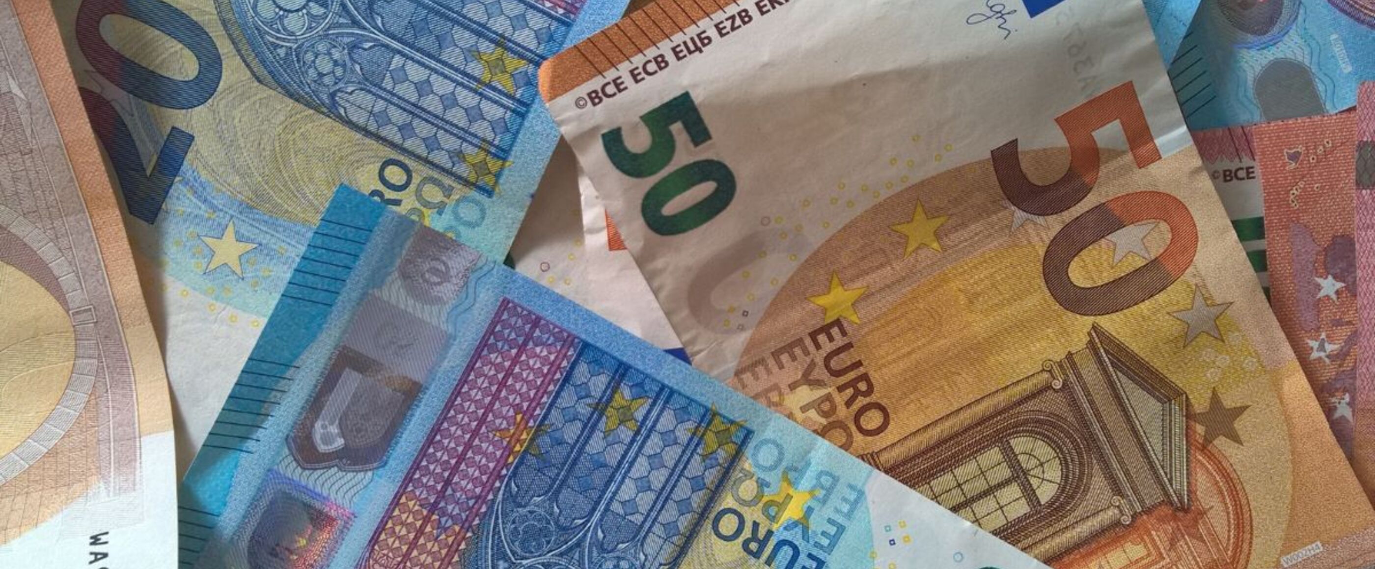 Blaue und gelbe und rote Euro-Scheine liegen durcheinander.