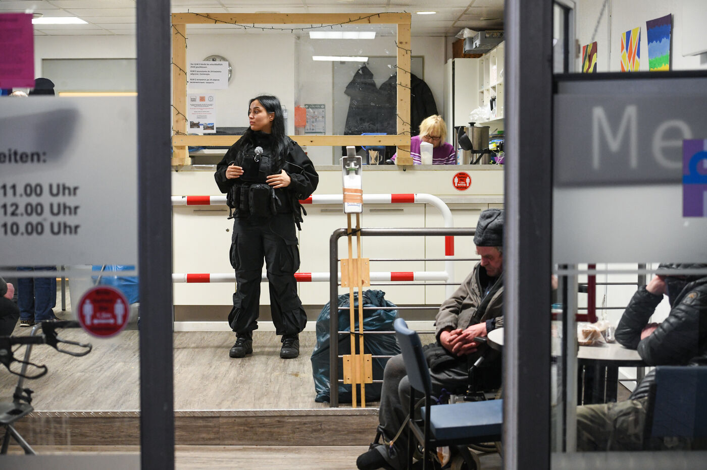 Eine junge Frau in Uniform steht in einem Obdachlosentreff und hält Wache.