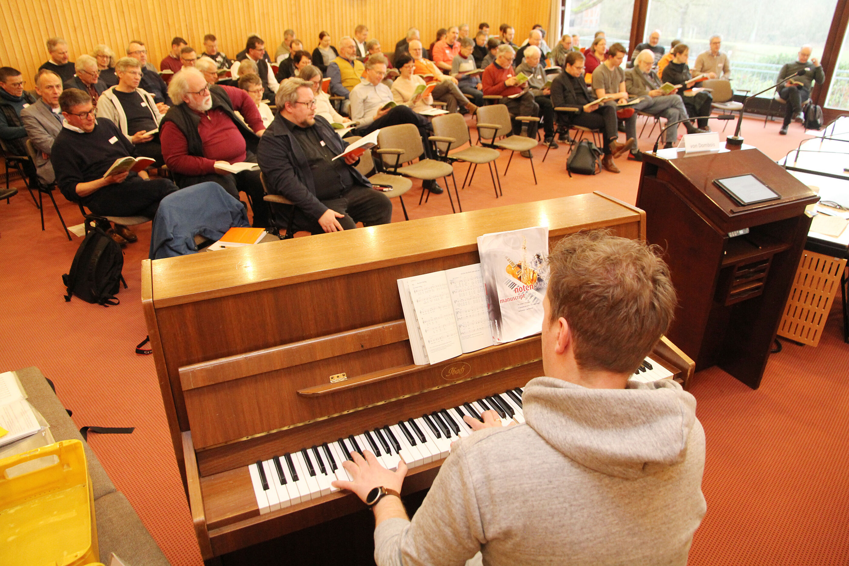 Popkantor Til von Dombois (am Klavier) singt mit den Tagungsteilnehmenden Neue Geistliche Lieder.
