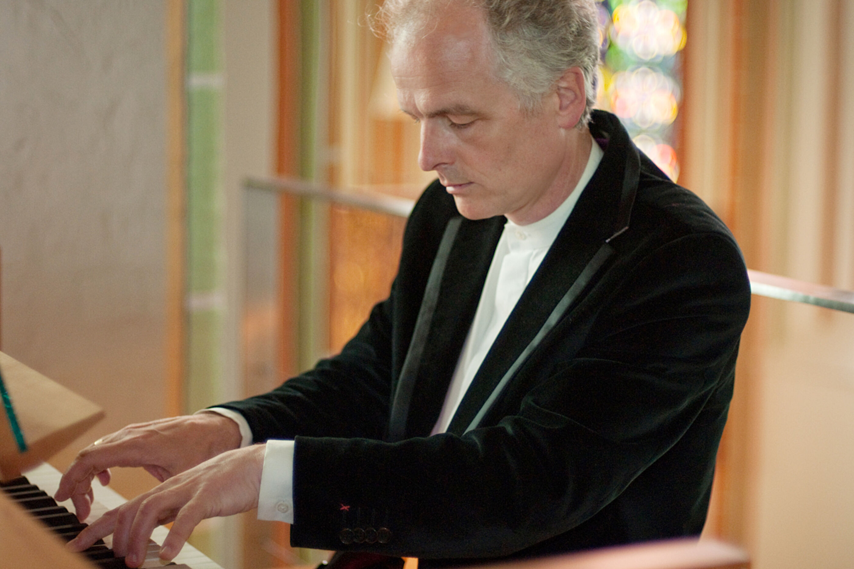 Ein Mann mit grauen Haaren spielt mit geschlossenen Augen die Orgel.