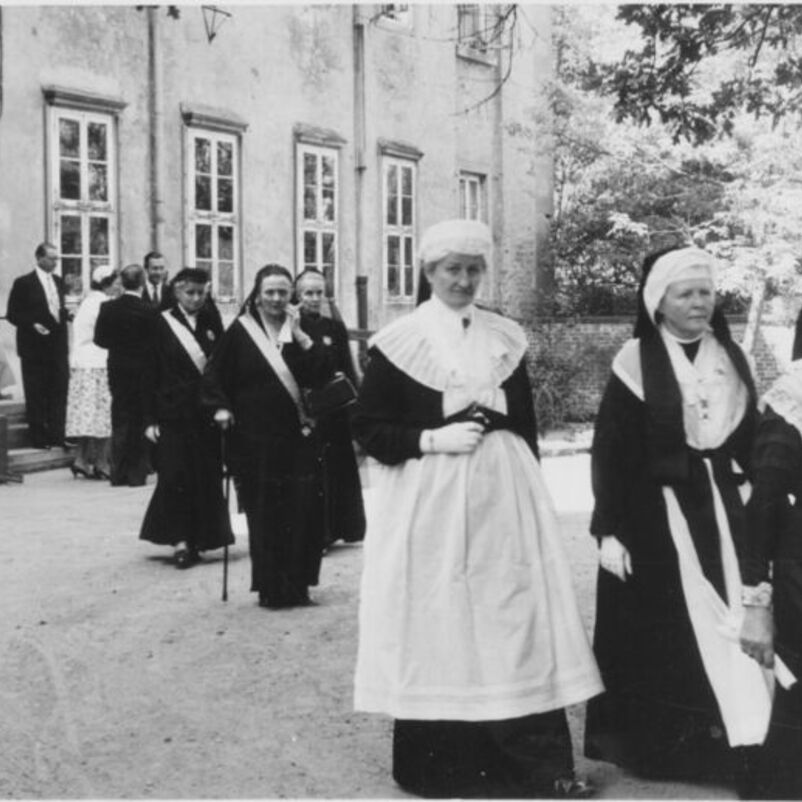 Das Schwarzweiß-Bild zeigt Äbtissinnen in ihrer Tracht auf dem Weg über einen Klosterhof. 