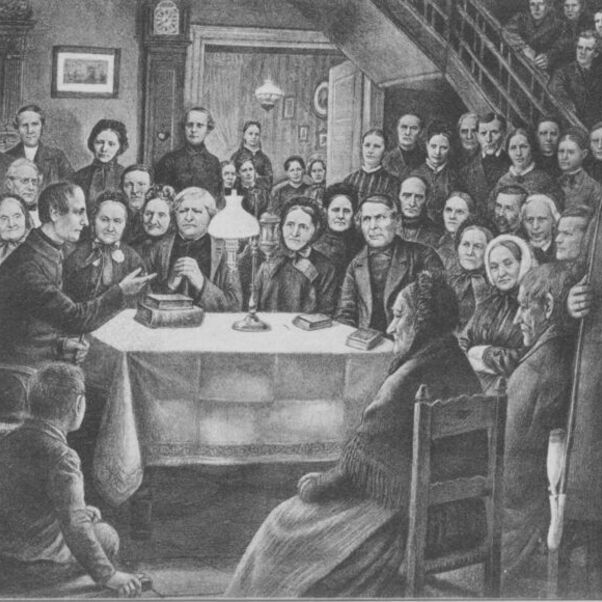 Das Bild zeigt einen Schwarzweiß-Stich mit vielen Menschen, die um einen Tisch herum stehen, an dem ein Pastor aus der Bibel vorliest.
