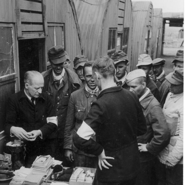Das Schwarzweiß-Bild zeigt einen Versorgungsstand für Kriegsheimkehrer mit vielen Menschen dicht gedrängt drumherum.