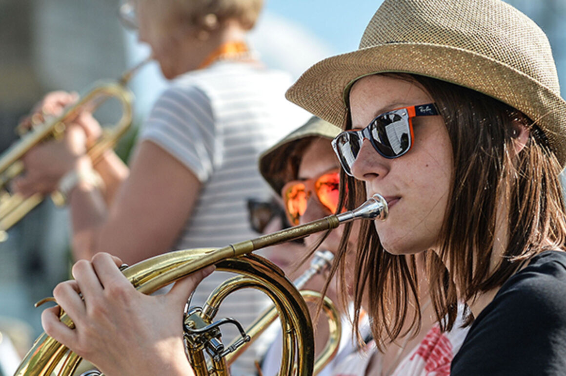 Eine junge Frau mit Sonnenbrille spielt Horn